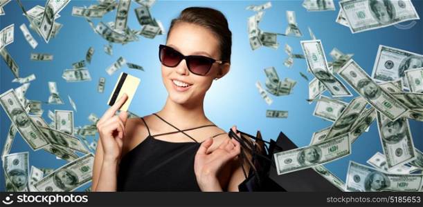 sale, finances, people and luxury concept - happy beautiful young woman in black sunglasses with credit card and shopping bags over gray background. happy woman with credit card and shopping bags