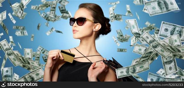 sale, finances, people and luxury concept - happy beautiful young woman in black sunglasses with credit card and shopping bags over gray background. happy woman with credit card and shopping bags