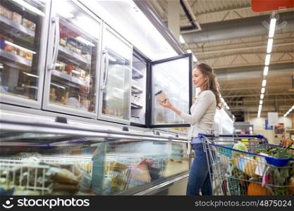 sale, food, consumerism and people concept - woman with shopping cart choosing ice cream at grocery store freezer