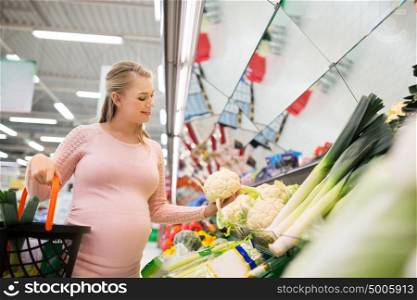 sale, food, pregnancy and people concept - happy pregnant woman with shopping basket buying cauliflower at grocery store or supermarket. happy pregnant woman buying cauliflower at grocery