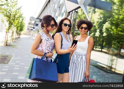 sale, friendship and technology concept - happy young women with shopping bags taking selfie by smartphone in summer city. women with shopping bags taking selfie in city