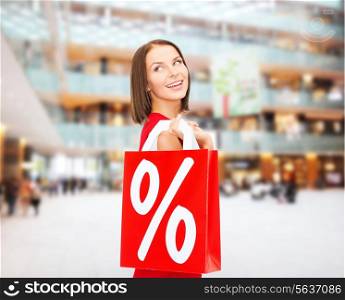 sale, gifts, christmas, holidays and people concept - smiling woman in red dress with shopping bags and percent sign