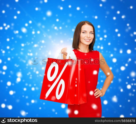 sale, gifts, christmas, holidays and people concept - smiling woman in red dress with shopping bags and percent sign over blue snowy background