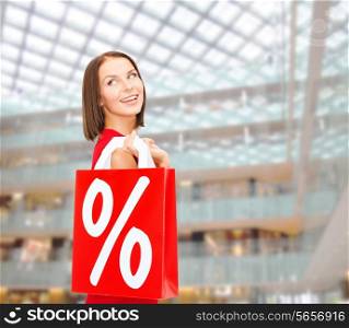 sale, gifts, christmas, holidays and people concept - smiling woman in red dress with shopping bags and percent sign