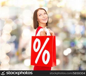 sale, gifts, christmas, holidays and people concept - smiling woman in red dress with shopping bags and percent sign over lights background