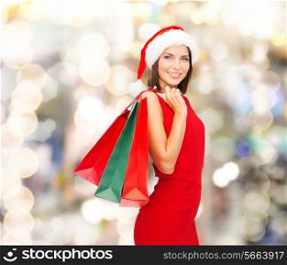 sale, gifts, christmas, holidays and people concept - smiling woman in red dress with shopping bags over lights background