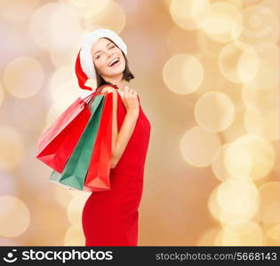 sale, gifts, christmas, holidays and people concept - smiling woman in red dress with shopping bags over beige lights background