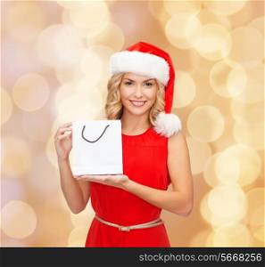 sale, gifts, christmas, holidays and people concept - smiling woman in red dress and santa helper hat with white blank shopping bag over beige lights background