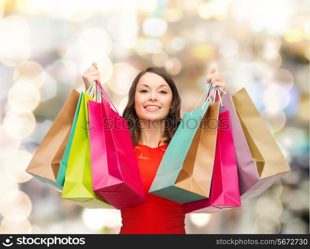 sale, gifts, christmas, holidays and people concept - smiling woman with colorful shopping bags over lights background