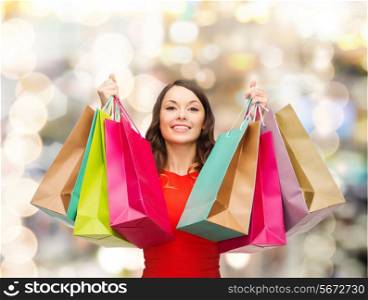 sale, gifts, christmas, holidays and people concept - smiling woman with colorful shopping bags over lights background