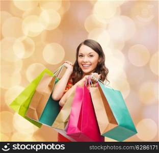 sale, gifts, christmas, holidays and people concept - smiling woman with colorful shopping bags over beige lights background