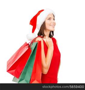 sale, gifts, christmas, x-mas concept - smiling woman in red dress and santa helper hat with shopping bags
