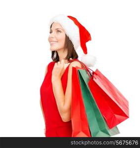 sale, gifts, christmas, x-mas concept - smiling woman in red dress and santa helper hat with shopping bags