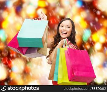 sale, gifts, christmas, x-mas concept - smiling woman in red dress with colorful shopping bags