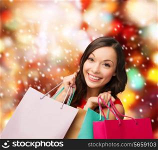 sale, gifts, christmas, x-mas concept - smiling woman in red dress with shopping bags