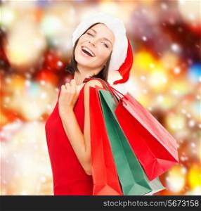 sale, gifts, christmas, xmas concept - smiling woman in red dress and santa helper hat with shopping bags