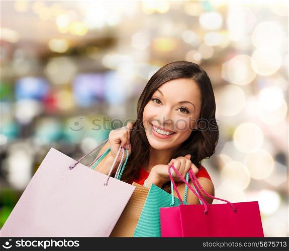 sale, gifts, christmas, xmas concept - smiling woman in red dress with shopping bags
