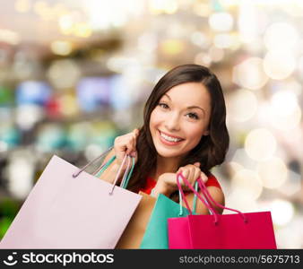 sale, gifts, christmas, xmas concept - smiling woman in red dress with shopping bags