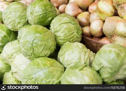sale, harvest, food, vegetables and agriculture concept - close up of cabbage and onion at street market