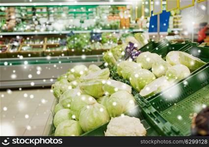 sale, harvest, food, vegetables and agriculture concept - close up of cabbage at grocery store or market over snow. close up of cabbage at grocery store or market