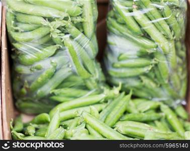 sale, harvest, food, vegetables and agriculture concept - close up of green peas in box at street market