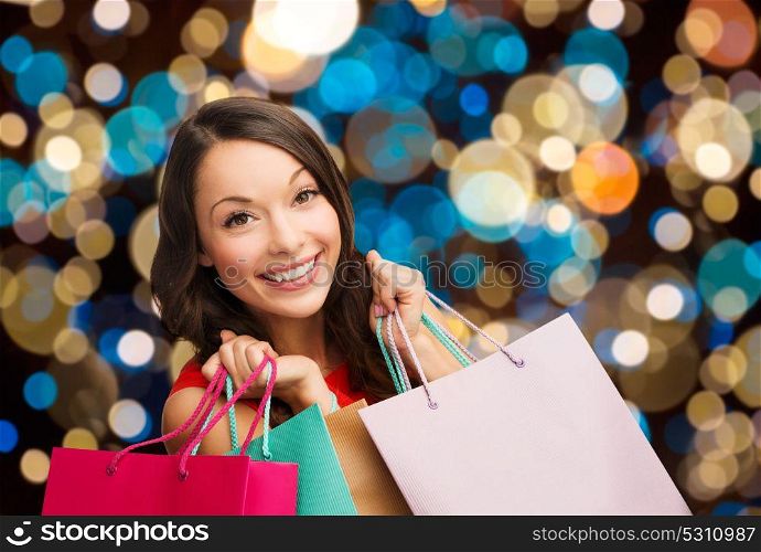 sale, holidays and people concept - smiling woman with shopping bags over lights background . smiling woman with colorful shopping bags