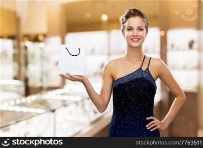 sale, luxury and people concept - smiling elegant woman in dress with small shopping bag over jewelry store background. smiling woman with shopping bag at jewelry store