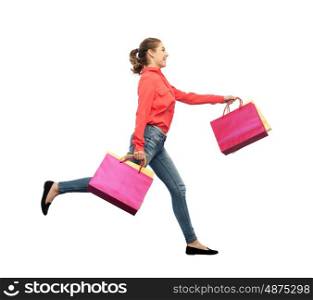 sale, motion and people concept - smiling young woman with shopping bags running in air over white background