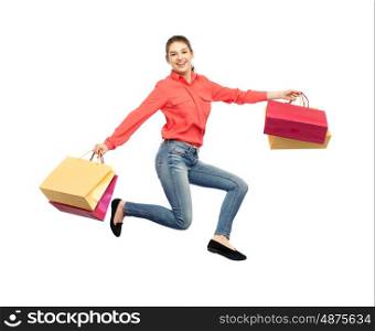 sale, motion and people concept - smiling young woman with shopping bags jumping in air over white background
