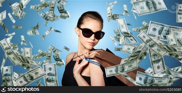 sale, people and luxury concept - happy beautiful young woman in black sunglasses with shopping bags. happy woman in black sunglasses with shopping bags