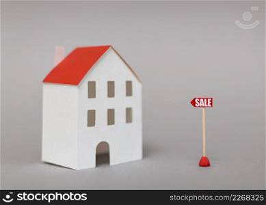 sale post near miniature house model against gray background