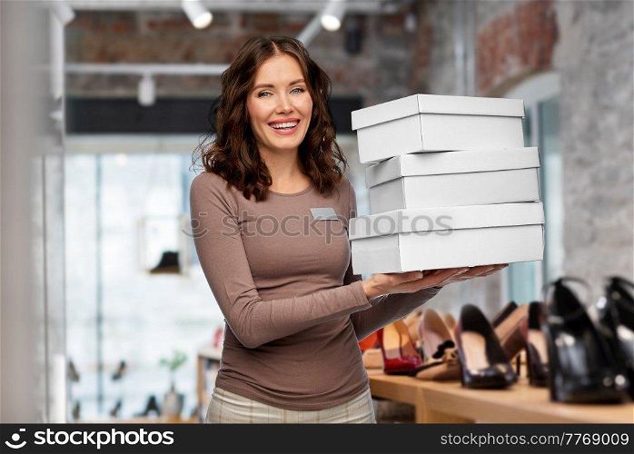 sale, shopping and business concept - happy female shop assistant or saleswoman holding three shoe boxes over store background. happy saleswoman holding shoe boxes at shop