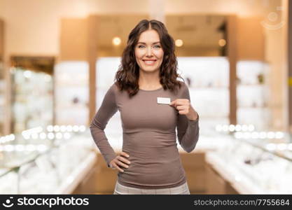 sale, shopping and business concept - happy female shop assistant showing her name tag over jewelry store background. female jewelry shop assistant showing her name tag