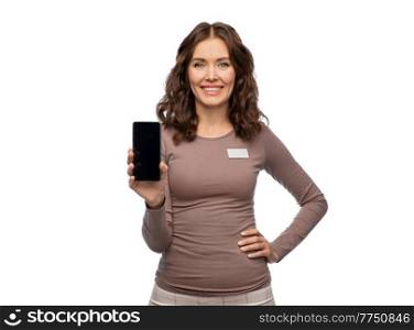 sale, shopping and business concept - happy female shop assistant with name tag showing smartphone over white background. happy female shop assistant showing smartphone