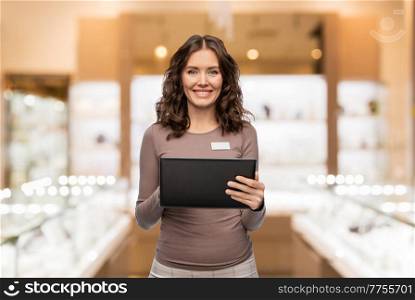 sale, shopping and business concept - happy female shop assistant with tablet pc computer name tag over jewelry store background. happy female jewelry shop assistant with tablet pc