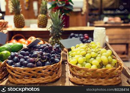 sale, shopping and eco food concept - ripe red and white grape in baskets with nameplates at grocery market