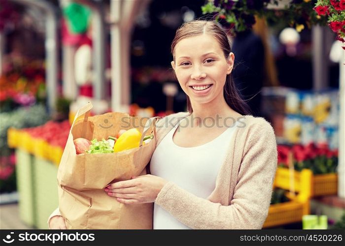 sale, shopping and people concept - happy woman with paper bag full of food at street market