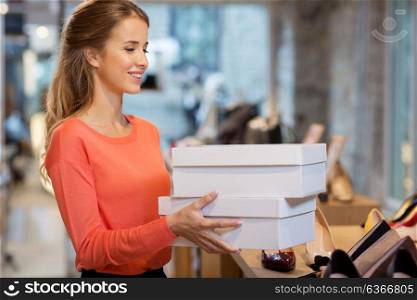 sale, shopping and people concept - happy young woman or shop assistant with shoe boxes at store. woman or shop assistant with shoe boxes at store
