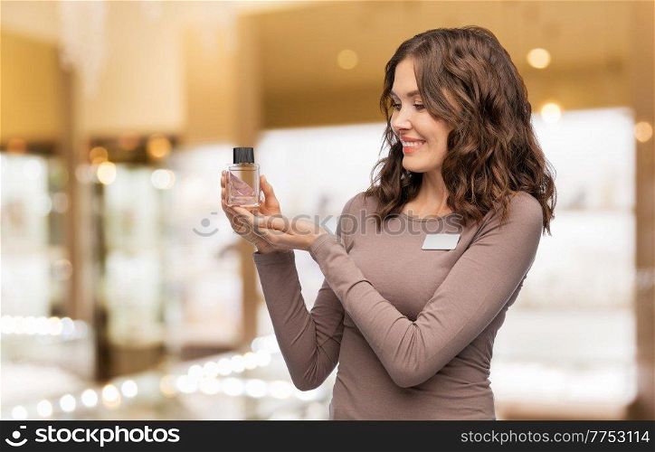 sale, shopping and perfumery concept - happy female assistant with perfume over shop background. happy female shop assistant with perfume