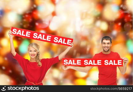 sale, shopping, christmas, holidays and people concept - smiling man and woman in red clothes with sale signs over lights background