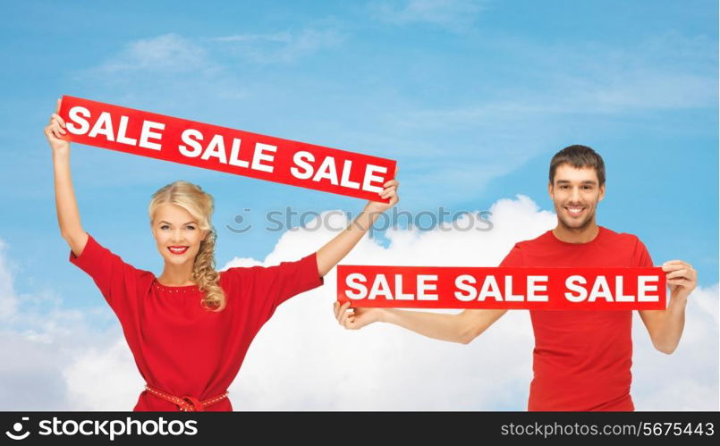 sale, shopping, christmas, holidays and people concept - smiling man and woman in red clothes with sale signs over blue sky and white cloud background