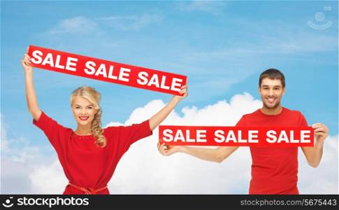 sale, shopping, christmas, holidays and people concept - smiling man and woman in red clothes with sale signs over blue sky and white cloud background