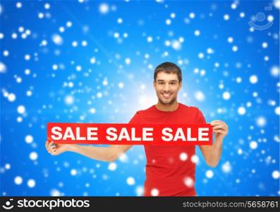 sale, shopping, christmas, holidays and people concept - smiling man in red t-shirt with sale sign over blue snowy background