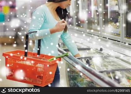 sale, shopping, consumerism and people concept - close up of female customer with food basket at grocery store freezer over snow. customer with food basket at grocery store freezer