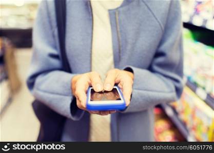 sale, shopping, consumerism and people concept - close up of woman with smartphone choosing and buying food in market
