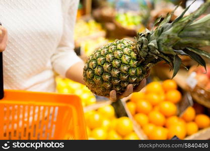 sale, shopping, consumerism and people concept - close up of young woman with food basket and pineapple in grocery market