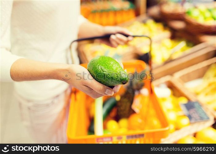 sale, shopping, consumerism and people concept - close up of young woman with food basket and avocado in market