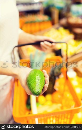 sale, shopping, consumerism and people concept - close up of young woman with food basket and avocado in market