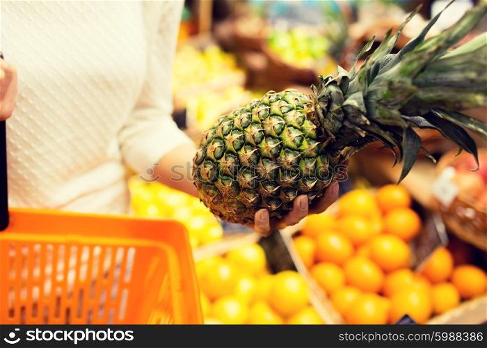 sale, shopping, consumerism and people concept - close up of young woman with food basket and pineapple in grocery market