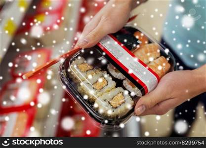 sale, shopping, consumerism and people concept - customer hands with sushi pack at grocery or supermarket over snow. hands with sushi pack at grocery or supermarket